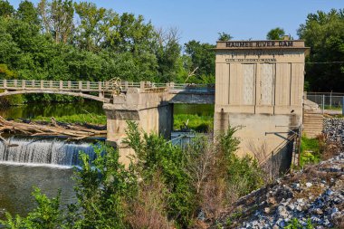 Maumee Nehri Barajı 'nın resmi, Fort Wayne, IN köprüsünün altındaki şelalenin tepesinde taşan kütüklerle birlikte tabeladadır.