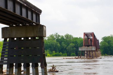 Karşıt Köprüler: Modern, sağlam bir beton ve çelik yapı geçmişten kalma paslı bir kalıntıyla birleşiyor. Bu sakin nehir kenarı sahnesi Evansville 'deki gelişim ve nostaljinin kesişimini yakalıyor.