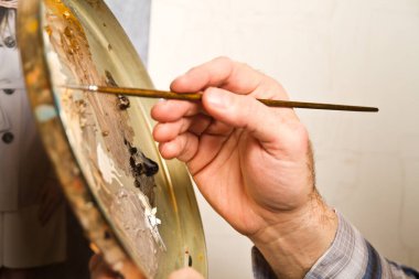 Yaratıcılığın ustaca vuruşları canlanıyor. Sanatçılar, yağlı boya paleti arasında ustalıkla kullanılmış bir boya fırçasını kullanırken. Bu büyüleyici görüntü sanatsal zanaatkarlığın özünü temsil ediyor.