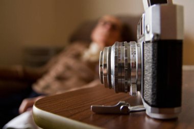 Vintage Ricoh 500 Film Kamerası, Konforlu İçerideki Yaşlı Büyükbabanın Nostaljik Anlarını Çekiyor