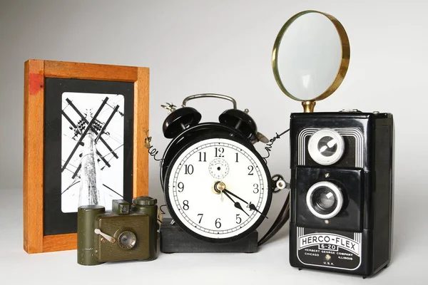 Vintage Photography Collection: A nostalgic assemblage of classic items including a Herco-Flex camera, twin-bell alarm clock, and magnifying glass, capturing the essence of retro charm and the passage