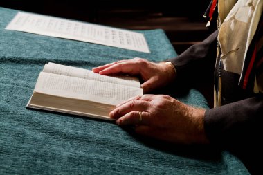 Resmî giysiler içinde, bir insan olarak huzurlu bir yansıma anı yaşlanmış elleri olan bir kitap okur. Arka plandaki notalar, okuma ve müzik arasındaki bağlantıyı işaret ediyor, muhtemelen bir dini ya da