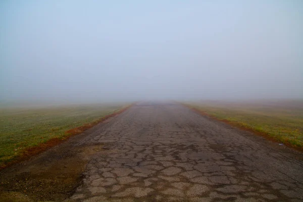 Journey into the Unknown: A weathered road disappears into the dense fog, symbolizing the uncertainty and solitude of exploration. Located in Fort Wayne, Indiana.
