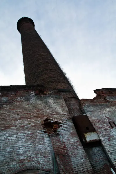 Industrial Relic: Abandoned brick chimney in Louisville, Kentucky, stands tall, covered in vines and showing signs of decay. A symbol of industrial decline and urban history.