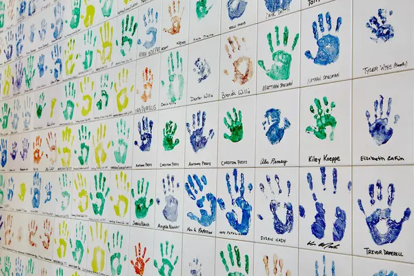 Vibrant handprint artwork adorns an indoor wall, showcasing individuality and community engagement in a school or art space. A colorful celebration of diversity, creativity, and unity.