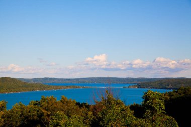Uçsuz bucaksız gökyüzünün altındaki yemyeşil tepelerin arasına yerleşmiş sakin bir göl. Dokunulmamış doğal güzellikler ve sakin bir atmosfer sunan pitoresk bir cennet..