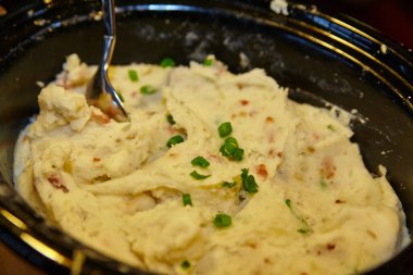 Lezzetli ev yapımı patates püresi, taze yeşil soğanla süslenmiş, siyah bir kâsede sunulmuş, Şükran Günü için mükemmel bir konfor yemeği ya da Fort Wayne 'deki herhangi bir sıcak yemek etkinliği için.