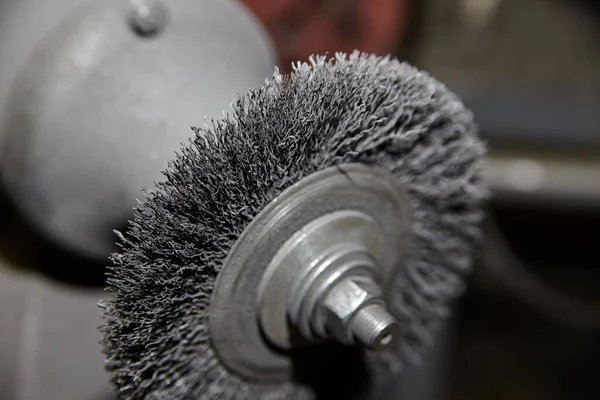 Close-up of a sharp, steel wire brush attached to a machine for metalworking tasks in an industrial workshop - ideal for machinery and maintenance content.
