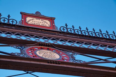 Tarihsel mimari ve açık mavi gökyüzüne karşı detaylı metal işçiliğinin yer aldığı Wrought Iron Bridge Co., Ft..