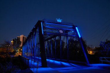Gece aydınlanması, Fort Wayne, Indiana 'daki Wells Caddesi Köprüsü' nün mimari güzelliğini canlı bir şehrin siluetine karşı sergiliyor..