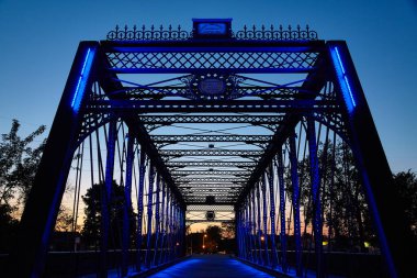 Alacakaranlık Fort Wayne, Indiana 'daki çarpıcı Wells Street Köprüsü' nü aydınlatır, LED ışıkları karmaşık çelik kiriş tasarımını vurgular. Tarihi cazibe ve modern estetiğin bir karışımı, mükemmel.