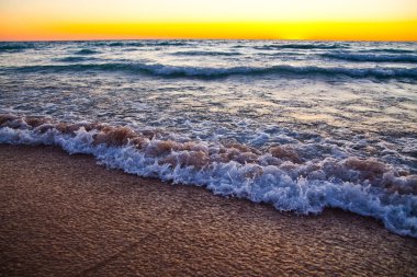 Michigan Gölü kıyılarında sakin bir gün batımı, kumlu sahilde kırılan nazik dalgaların büyüleyici güzelliğini yakalıyor..