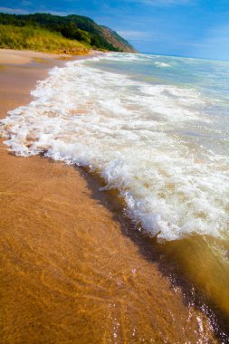 Michigans 'ın çarpıcı kıyı şeridi boyunca gözlerden uzak bir plajın dinginliğini hissedin. Yumuşak esintiyi hisset köpüklü dalgalar, yemyeşil bir tepe tarafından çerçevelenmiş altın kumlar üzerinde kırılırken. Seyahat için mükemmel.