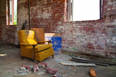 Yalnızlık ve çürüme: İndiana, Pierceton 'da terk edilmiş bir binanın ıssız ortasında eski bir koltuk bulunuyor. Doğal ışık eskimiş döşemeleri ve yıpranmış tuğla duvarları aydınlatır..