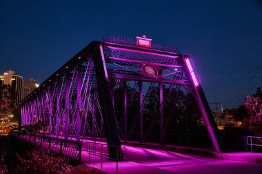 Fort Wayne, Indiana 'daki Twilight' ta canlı ışıklandırılmış çelik kiriş köprüsü mimari detaylar ve şehir gece hayatı sergileniyor..