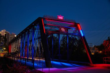 Fort Wayne, Indiana 'daki canlı Wells Caddesi Köprüsü' nün alacakaranlık manzarası, karmaşık çelik kiriş tasarımı ve büyüleyici mimari ışıklandırması sergileniyor..