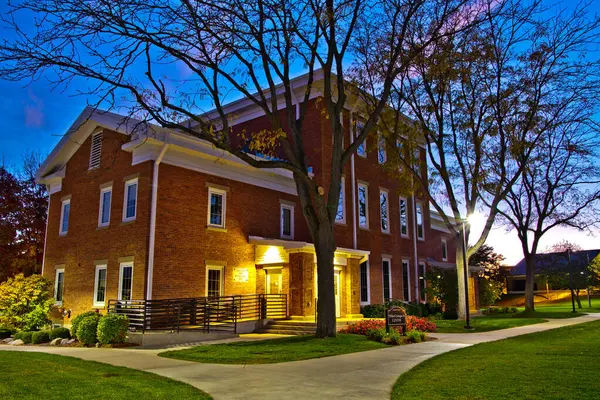 Serene twilight at a classic brick community center in Fort Wayne, Indiana. Warm lighting illuminates the traditional architecture. Perfect for marketing local services and highlighting community