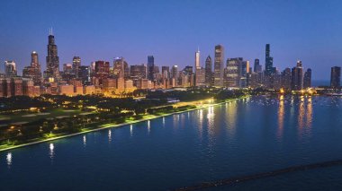 Gece vakti Michigan Gölü 'nün liman yakınındaki suyuna yansıyan şehir ışıklarıyla Chicago sahili havası görüntüsü