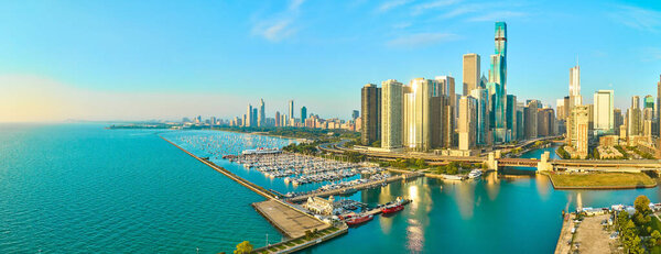Aerial panorama of Chicagos vibrant skyline, serene Lake Michigan marina, and modern skyscrapers in golden hour light