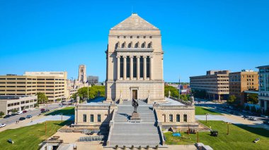 Indianapolis 'teki büyük neoklasik Indiana Dünya Savaşı Anıtı' nın gündüz hava görüntüsü sakin yeşil çimenler ve tarihi hürmetle dolu şehir hayatıyla çelişiyor.