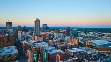 Alacakaranlıkta Indianapolis şehir merkezi, Gainbridge Fieldhouse 'u gösteren hava manzarası, önde gelen gökdelenler ve aktif şehir yaşamı, 2023 yılında DJI Mavic 3 insansız hava aracı ile yakalandı..