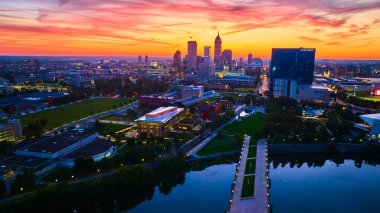 Indianapolis üzerinde gün doğumu: Gökyüzü manzaralı gökyüzü manzaralı yüksek binalar altın saatin tadını çıkarıyor, sakin Beyaz Nehir 'de yansıtılıyor.