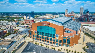 Indianapolis 'teki Lucas Petrol Stadyumu' nun havadan görünüşü, kırmızı tuğlalı cephesi ve geri çekilebilir çatısı ile modern bir mimari harikası, canlı kentsel manzaraya sahip..