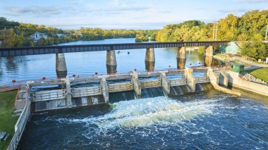 Huron River, Michigan 'da altın saat, Argo Barajı, bir demiryolu köprüsü, ve sakin manzaranın tadını çıkaran kano oyuncuları