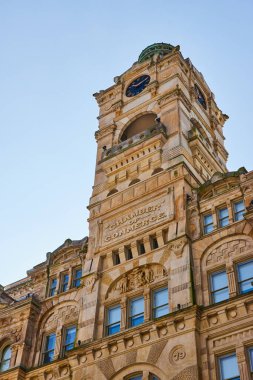 Süslü kumtaşı tasarımı, uzun saat kulesi ve açık mavi gökyüzü altındaki yeşil kubbe ile Büyük Ticaret Odası binası Milwaukee, Wisconsin, 2023