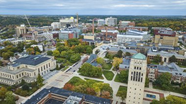 Michigan Üniversitesi kampüsünün hava görüntüsü, canlı sonbahar renkleri, ikonik Burton Anıt Kulesi ve Ann Arbor 'daki modern gelişmeler.