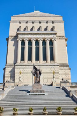 Indianapolis şehir merkezindeki neoklasik bir yapı olan Indiana Dünya Savaşı Anıtı 'nın gündüz görüntüsü, 2023 yılında bronz bir heykel ve büyük bir merdivenle.