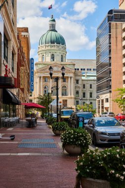 Indianapolis şehir merkezinin canlı gündüz manzarası, eklektik mimari, kafeli hareketli bir sokak manzarası, ve ikonik neoklasik adliye binası, 2023.