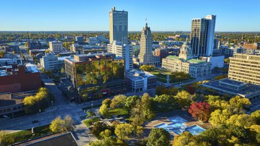 Fort Wayne, Indiana şehir merkezinde günbatımı modern gökdelenleri, seçkin adliyesi ve Freimann Meydanı Parkı 'ndaki sonbaharın canlı renkleri ile hareketli bir şehrin havadan görünüşü..