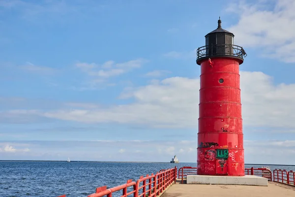 2023 yılında Milwaukee, Wisconsin 'deki bir rıhtımda, güneşli bir günde açık deniz ve mavi gökyüzü manzaralı, deniz güvenliği ve kıyı güzelliği sağlayan canlı kırmızı bir deniz feneri..