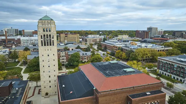 Aerial view of University of Michigan, featuring the historic Burton Memorial Tower, amidst a vibrant urban canvas of Ann Arbor.