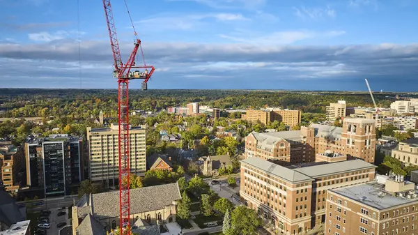 Aerial View of Urban Development in Downtown Ann Arbor, Michigan, featuring a Prominent Construction Crane amid Mixed-use Buildings, Captured by Drone in Daylight during Fall Season