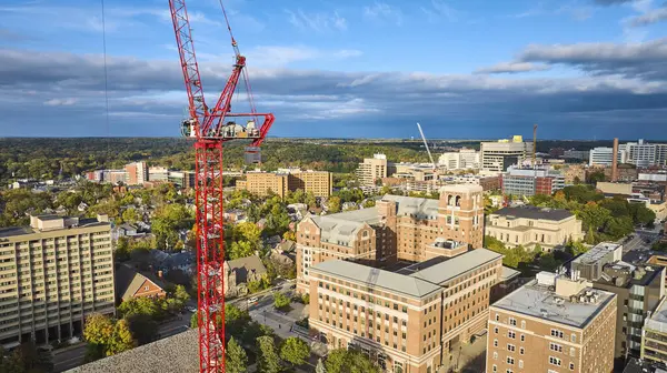 Aerial view of vibrant construction scene in downtown Ann Arbor, Michigan, showcasing a dominant red crane amid mixed-use buildings