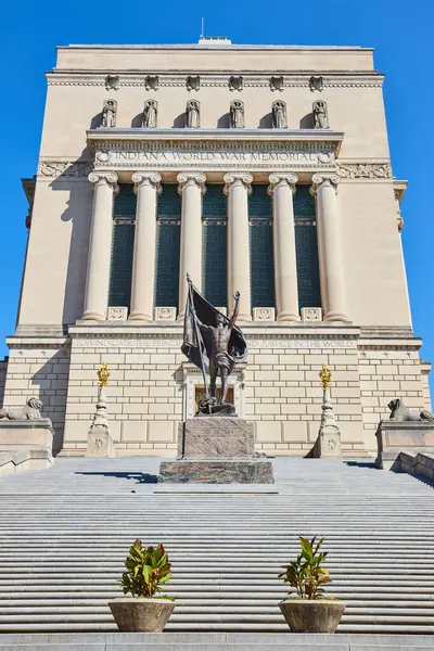 Neoklasik mimari ve bronz vatansever bir heykelin yer aldığı resmi Indiana Dünya Savaşı Anıtı, 2023 yılında Indianapolis şehir merkezinde açık mavi bir gökyüzü altında ele geçirildi..