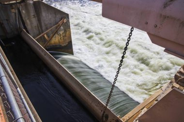 Michigan 'daki Argo Barajı' nın güneşli manzarası Huron Nehri 'nin yıpranmış çelik yapı ve kontrol zincirindeki çalkantılı akışını gösteriyor.