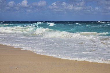 Nassau, Bahamalar 'daki Tropikal Cennet Adası Sahili açık mavi gökyüzü altında altın kumlu kıyılara çarpan canlı turkuaz okyanus dalgalarını sergiliyor.