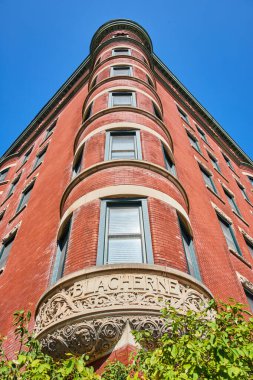 Indianapolis şehir merkezinde 2023 'te açık mavi gökyüzünün altında tarihi Blacherne kırmızı tuğla binası ve dekoratif mimari ve yeşillik sergileniyor.