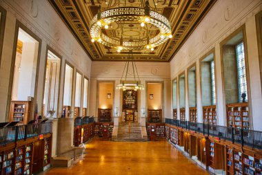 Bir Indianapolis kütüphanesinin görkemli avizesi, merdiveni ve geniş kitap koleksiyonu olan, uzun kemerli pencerelerden geçen gün ışığıyla aydınlatılan görkemli ve huzurlu iç mekanı..