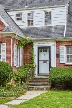 Ann Arbor, Michigan 'daki iki katlı banliyö evi bulutlu bir gökyüzünün altında sarmaşık aksanıyla beyaz ve tuğla karışımı bir şey sergiliyor..