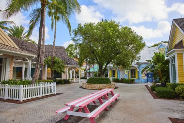 Nassau, Bahamalar 'daki canlı tropikal alışveriş köyünde pastel renkli binalar, pembe bir piknik masası ve yemyeşil palmiye ağaçları yer alıyor..