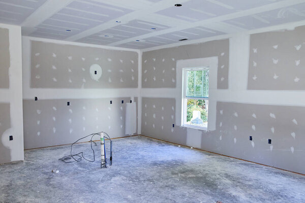 Daylight brightens a work-in-progress room in Fort Wayne, Indiana, featuring bare walls, a concrete floor, and a lone stepladder, symbolizing transformation and potential.
