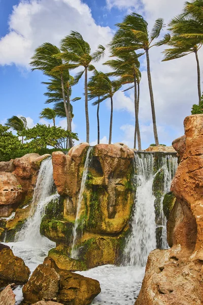 Tropical Paradise, featuring a stunning waterfall nestled in lush greenery under a blue sky on Paradise Island, Nassau, Bahamas