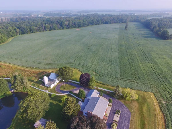 Early morning aerial view of a serene rural landscape with a green farmland, classic white barn and a beautiful country house in Auburn, Indiana, 2015