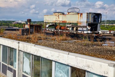 Terk Edilmiş Günler Oteli 'nin çatısı Kuzey Randall, Ohio' da paslanmış HVAC birimleri ve aşırı büyümüş yeşilliklerle kentsel bozulmayı gösteriyor.