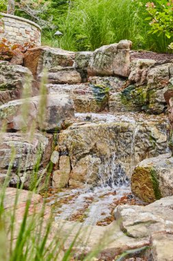 Kırsal şelale, sakin bir bahçe olan Huntertown, Indiana 'da, yosunlu kayaların üzerinde çağlayarak ilerliyor.