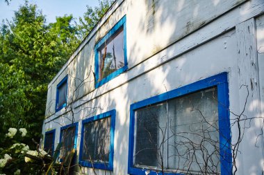 2015 'te terk edilmiş Indiana eğlence merkezi hız treni binası, yıpranmış beyaz duvarları, kırılmış mavi pencere çerçeveleri ve doğa geri istiyor..